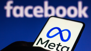 In this screenshot, the Meta logo can be seen placed on a smartphone behind the Facebook logo